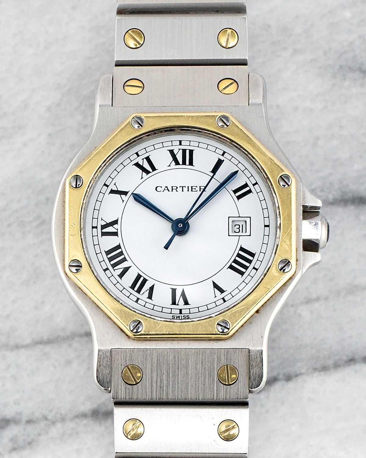 Close view of a two-tone Santos Octagon 2966: gold octagonal bezel with screws, white lacquer Roman dial, blued hands and date at three. · Photo: Danny's Vintage Watches · © Danny's Vintage Watches, used with permission · Source: https://dannysvintagewatches.com/products/cartier-santos-octagon-2966-white-roman-dial